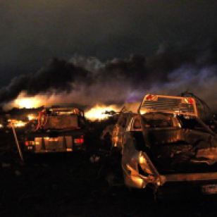 Vehicles are seen near the remains of a fertilizer plant burning after an explosion at the plant in the town of West, near Waco, Texas early April 18, 2013. The deadly explosion ripped through the fertilizer plant late on Wednesday, injuring more than 100 people, leveling dozens of homes and damaging other buildings including a school and nursing home, authorities said. REUTERS/Mike Stone