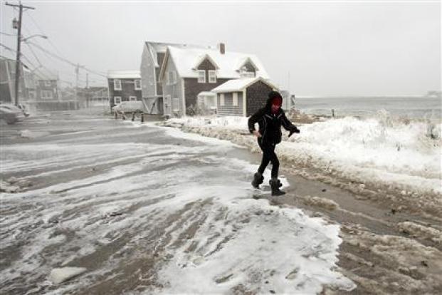 A woman runs from the surf as waves crash into houses on Lighthouse Road during a winter nor'easter snow storm in Scituate, Massachusetts January 3, 2014. REUTERS/Dominick Reuter.