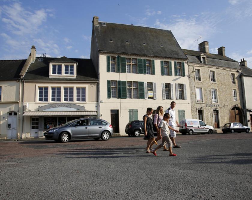 Tourists walk across the main square of Place Du Marche near the former D-Day landing zone of Omaha Beach, in Trevieres, France August 23, 2013. (REUTERS/Chris Helgren)