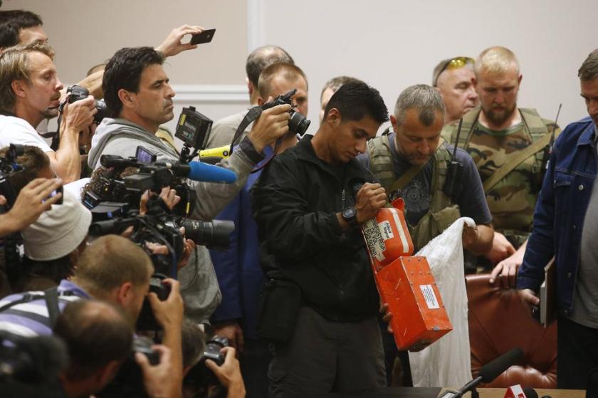A Malaysian expert (C) examines a black box belonging to Malaysia Airlines flight MH17 during its handover from pro-Russian separatists, in Donetsk July 22, 2014. The remains of some of the 298 victims of the Malaysia Airlines plane downed over Ukraine were making their way to the Netherlands on Tuesday as Senior Ukrainian separatist leader Aleksander Borodai handed over the plane's black boxes to Malaysian experts. REUTERS/Maxim Zmeyev